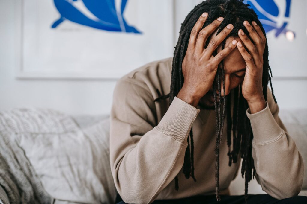 crop unhappy black man with headache on sofa at home