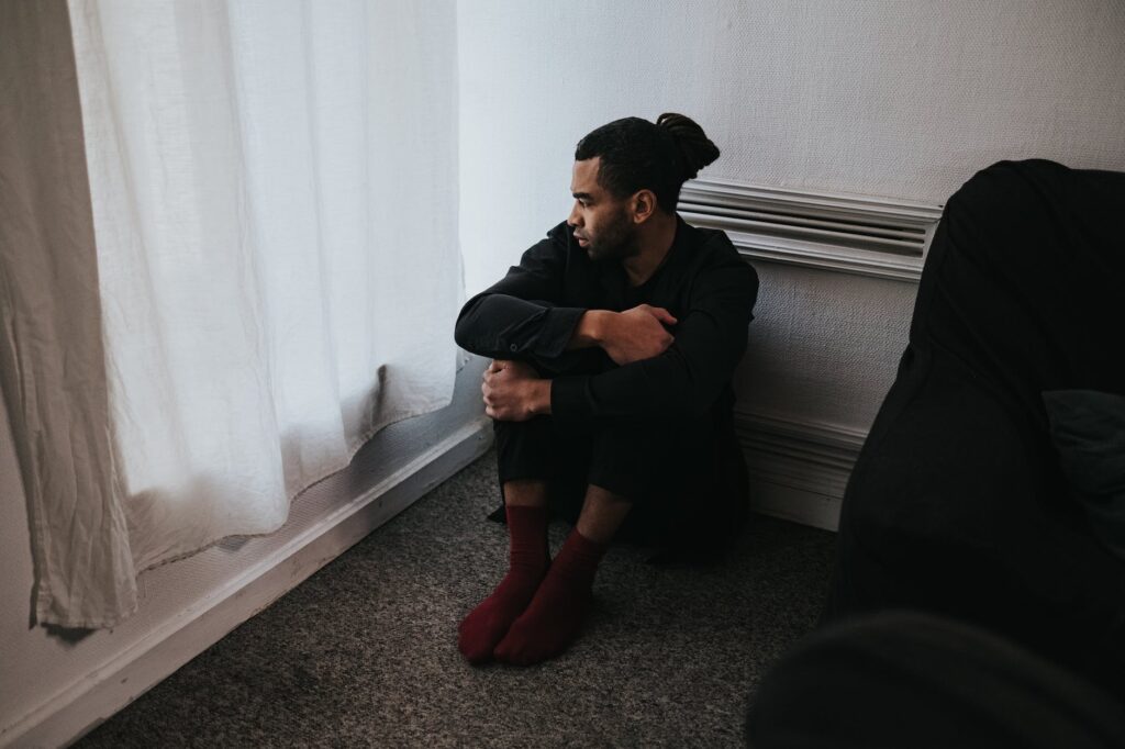 man in black jacket and red pants sitting on floor