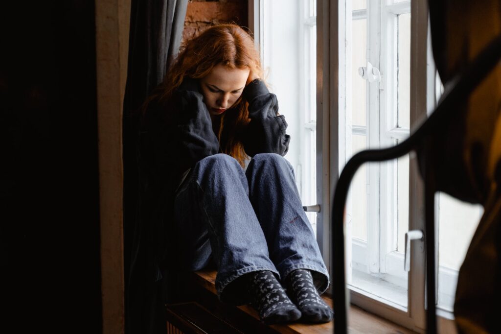 depressed woman sitting by the window